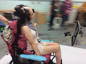 A blurred image of a girl in a wheelchair being pushed across a large piece of white paper